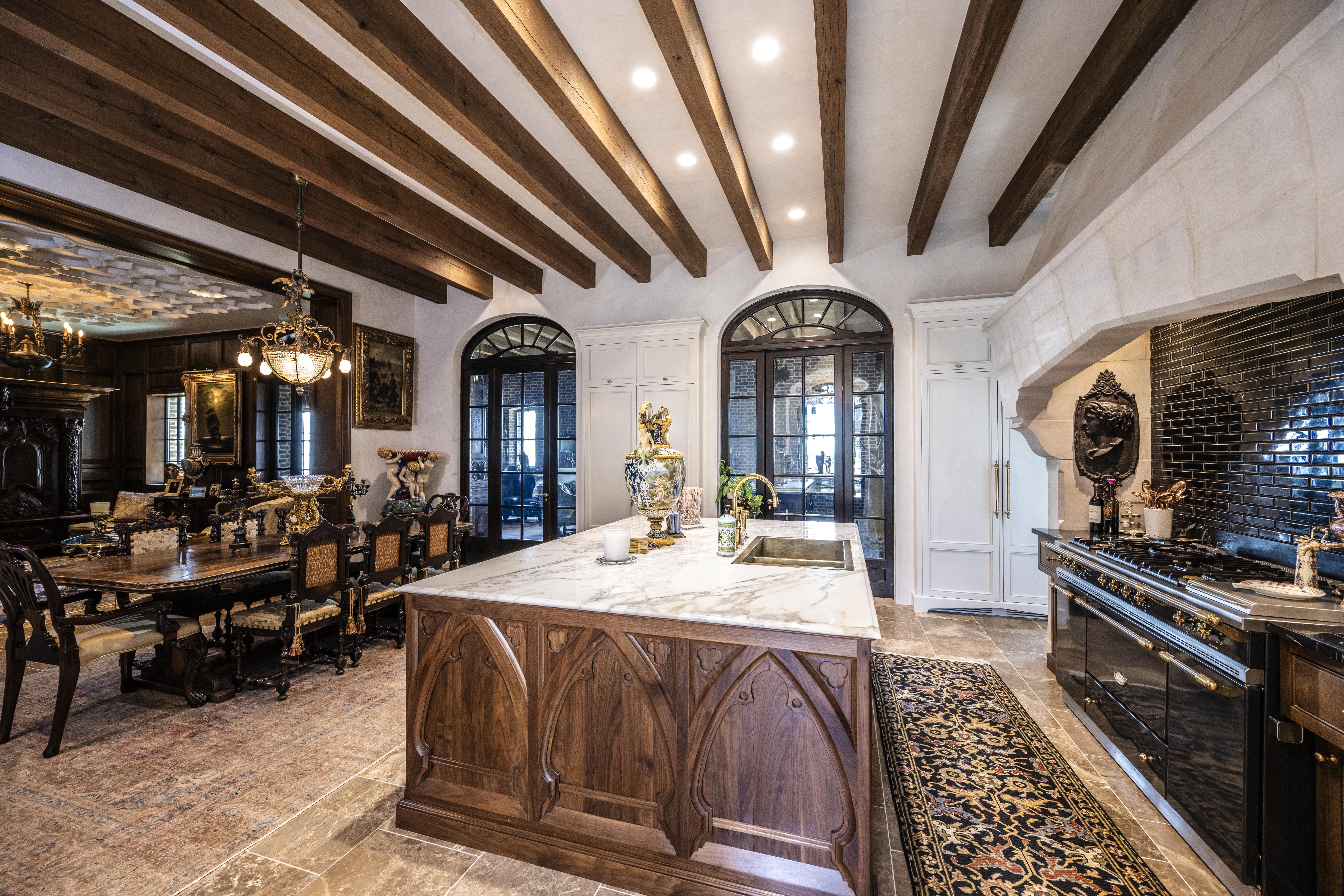 Editorial view of a residential kitchen with cream Venetian plaster walls beneath dark wood beams, Ravencliff Residence, photographed by Danny Gale