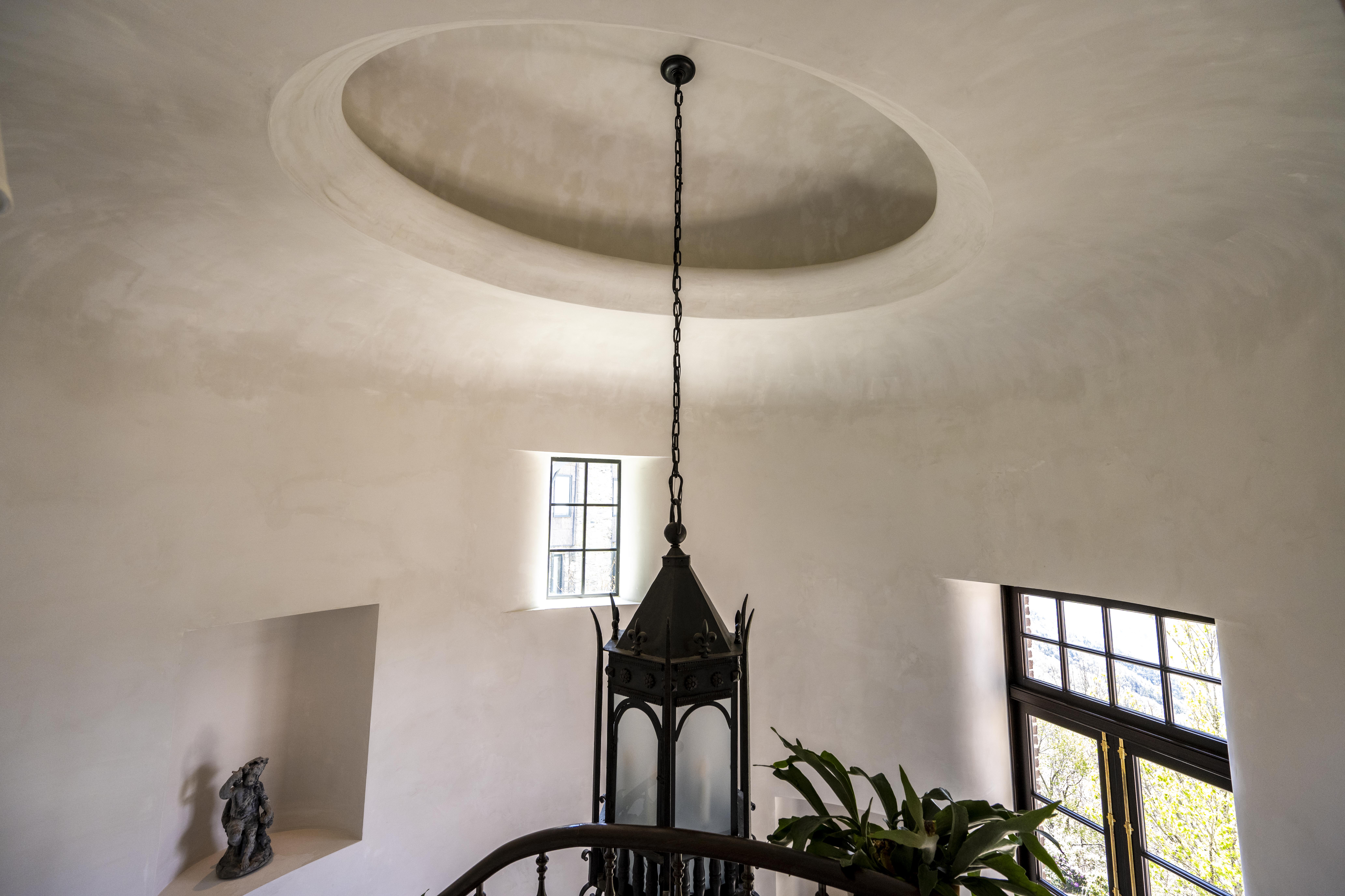 Suede-finish Venetian plaster wall with even sheen across a continuous plane, residential interior, raking light from a side window