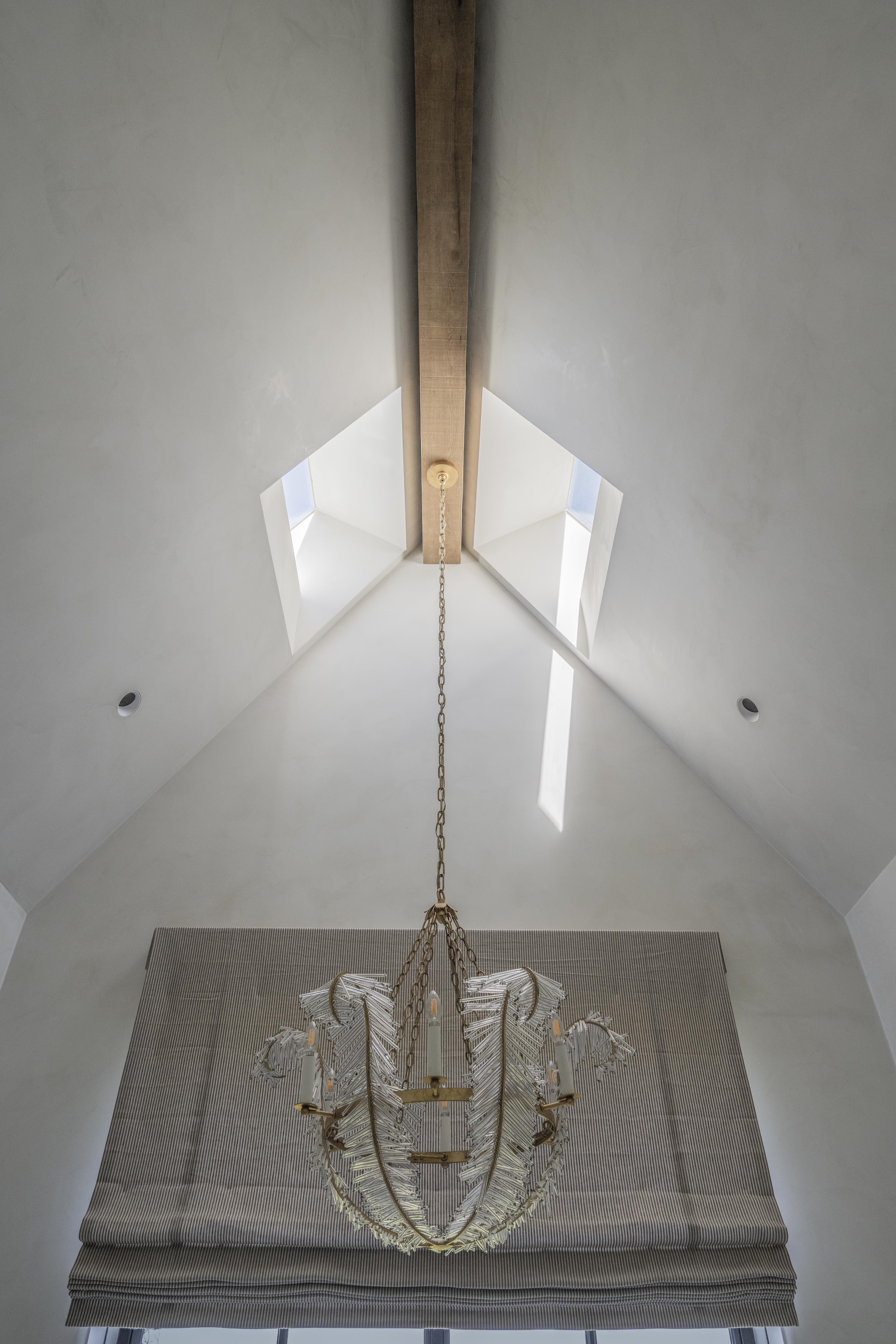 Soft cream limestone plaster wall in raking afternoon light, Tudor revival entry hall in Asheville